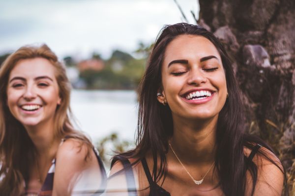 Dental Veneers Newport. Image of two ladies outside by a tree smiling.