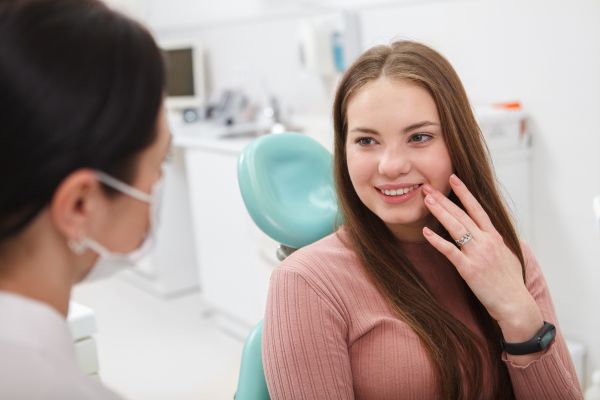 Smile Design - woman sitting in dentist chair talking to dentist