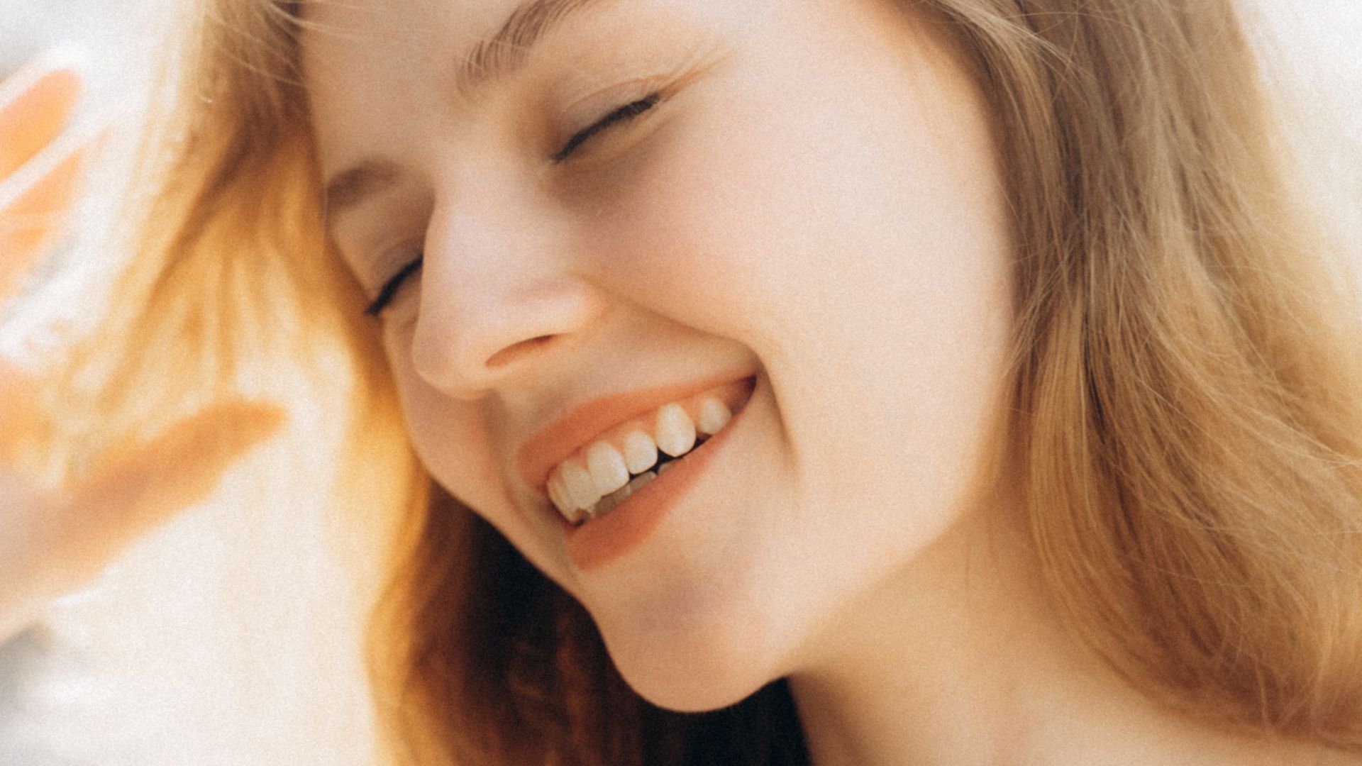 Close-up photo of a woman smiling. She has her eyes closed.