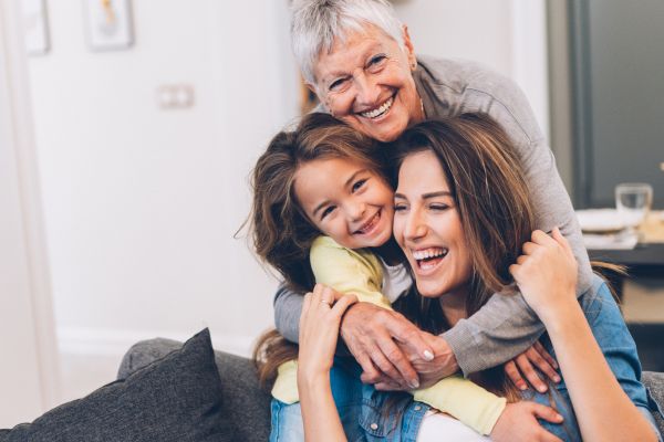 Photo of a grand mother, daughter and grand daughter hugging.
